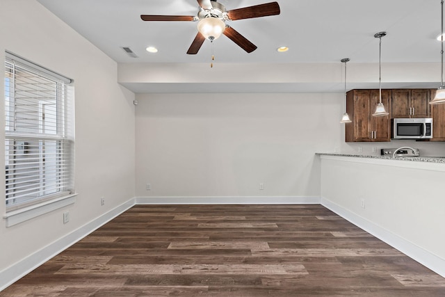 interior space featuring dark wood-style floors, visible vents, a ceiling fan, and baseboards