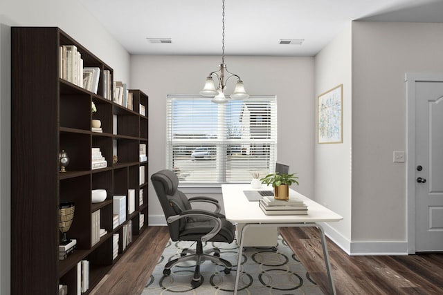 office area with visible vents, a notable chandelier, dark wood finished floors, and baseboards