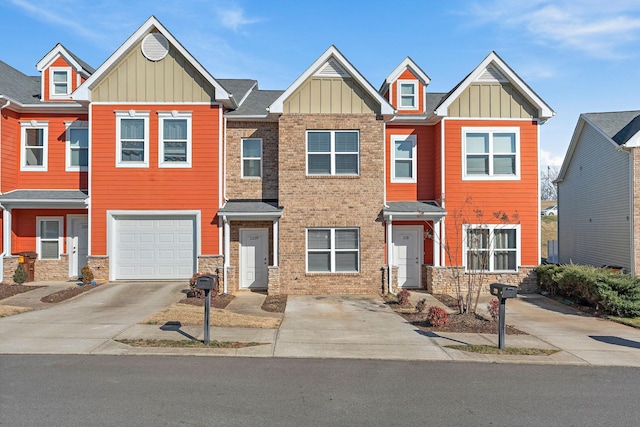 townhome / multi-family property with board and batten siding, concrete driveway, and stone siding