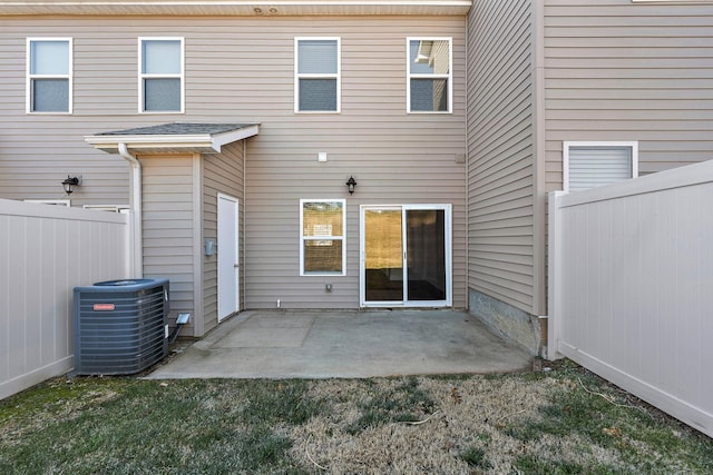 rear view of property featuring a patio, central air condition unit, a lawn, and fence