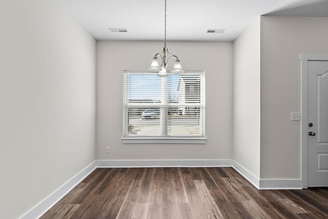 unfurnished dining area featuring dark wood finished floors, an inviting chandelier, baseboards, and visible vents