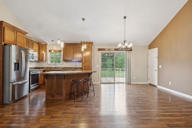 kitchen with an inviting chandelier, brown cabinets, dark wood-style flooring, stainless steel appliances, and vaulted ceiling