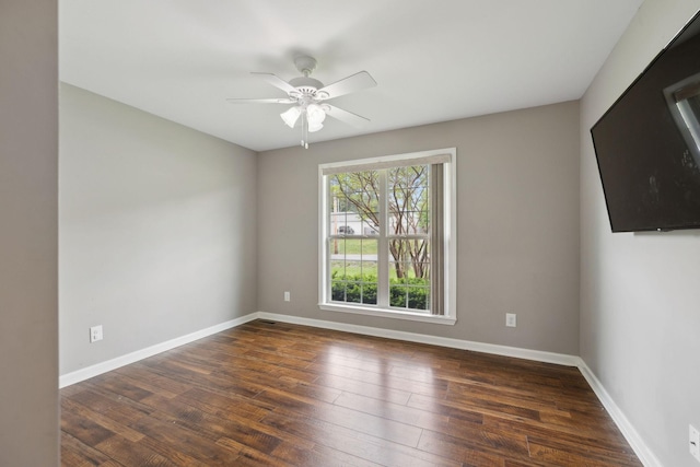 empty room featuring a ceiling fan, dark wood finished floors, and baseboards