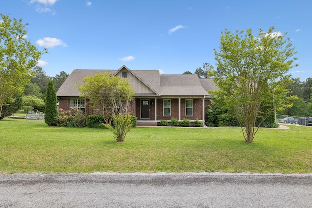 view of front of house with a porch, a front yard, and brick siding