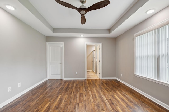 unfurnished bedroom with baseboards, a raised ceiling, and wood finished floors