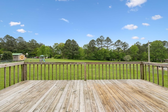 wooden terrace with an outbuilding, a storage shed, a yard, and a playground