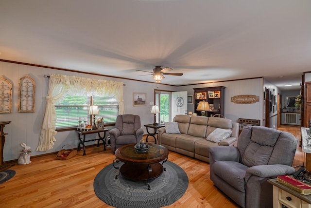 living area with crown molding, a ceiling fan, and wood finished floors