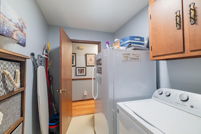 laundry room featuring cabinet space, light tile patterned flooring, a wainscoted wall, and washer / clothes dryer