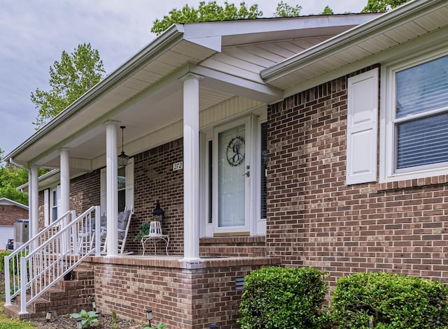doorway to property featuring covered porch and brick siding
