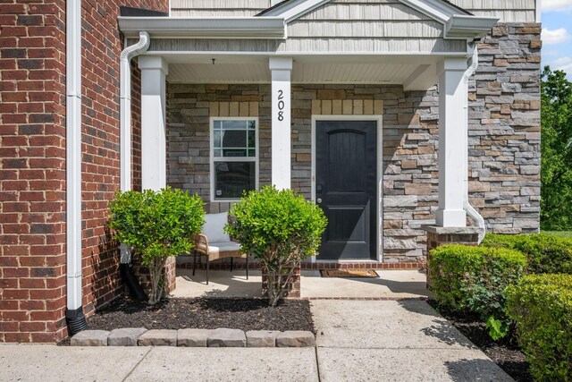 208 Wyburn Pl, Burns, TN 37029 - view of exterior entry featuring a porch and brick siding
