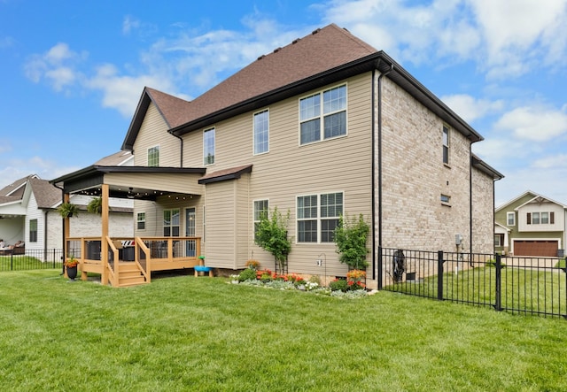 rear view of property featuring brick siding, fence, a yard, and a wooden deck