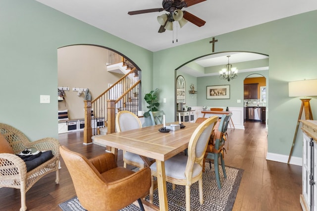 dining room with arched walkways, ceiling fan with notable chandelier, stairway, and hardwood / wood-style flooring