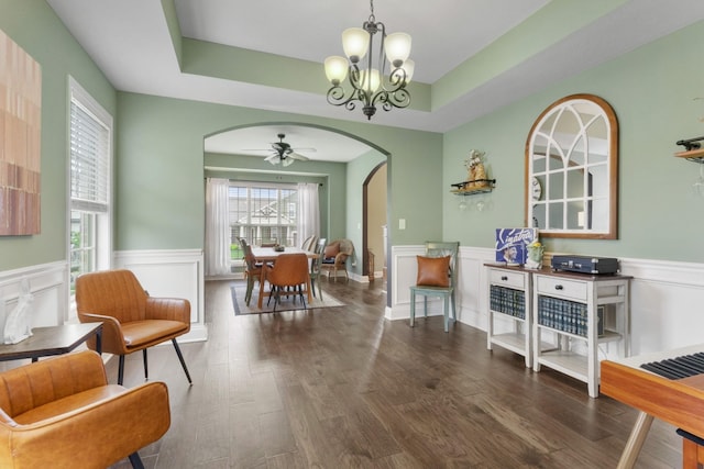 living area featuring arched walkways, wainscoting, ceiling fan with notable chandelier, and wood finished floors