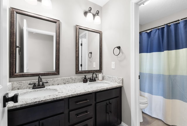 bathroom featuring double vanity, toilet, and a sink