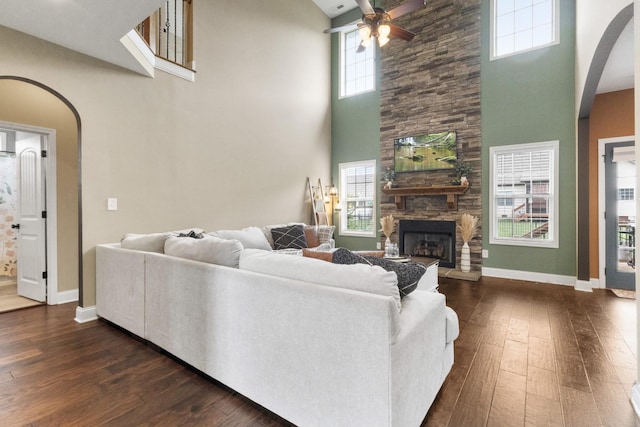 living room with arched walkways, a high ceiling, a ceiling fan, and dark wood-type flooring