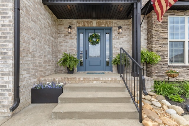 view of exterior entry featuring a porch and brick siding