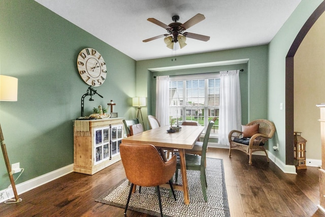 dining room with arched walkways, ceiling fan, baseboards, and wood finished floors