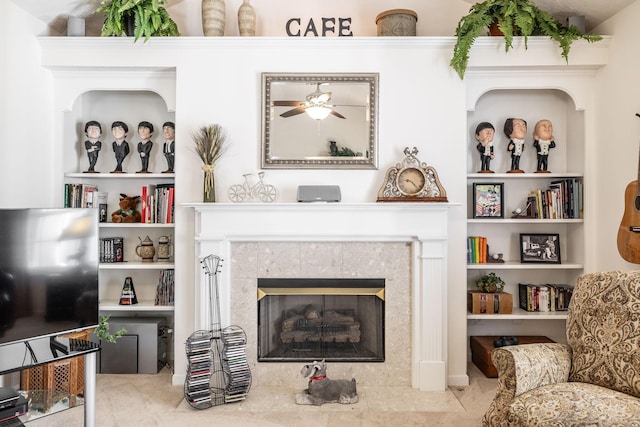 living area featuring a tiled fireplace and ceiling fan