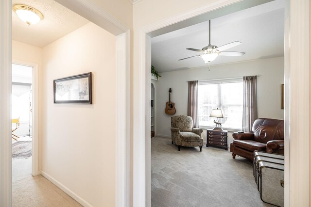living area with baseboards, carpet, and a ceiling fan