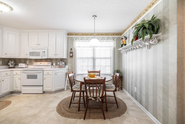 kitchen with light countertops, wallpapered walls, white appliances, and white cabinetry