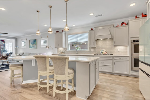 1072 Sumner Grv, Spring Hill, TN 37174 - kitchen with a breakfast bar area, light countertops, custom exhaust hood, open floor plan, and ornamental molding