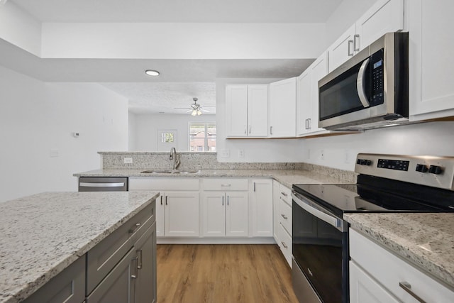 kitchen featuring white cabinets, stainless steel appliances, ceiling fan, and a sink