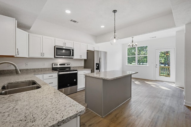 kitchen with dark wood finished floors, stainless steel appliances, a center island, a sink, and visible vents