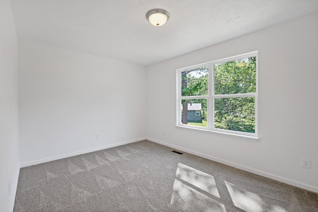 empty room featuring carpet, visible vents, and baseboards