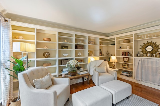 sitting room with wood finished floors, built in shelves, and ornamental molding