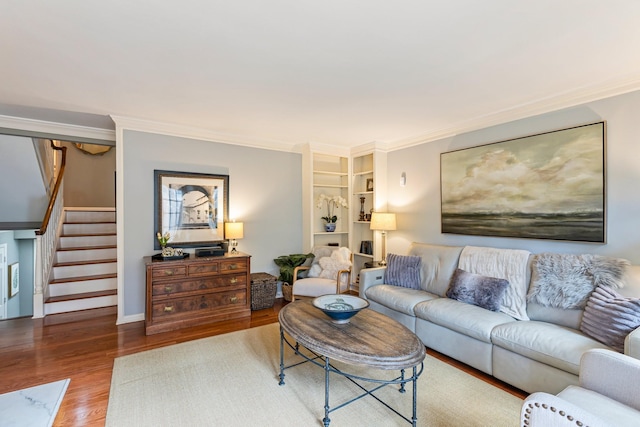living area featuring wood finished floors, ornamental molding, built in features, and stairs