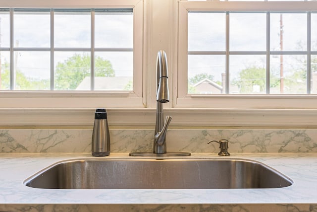 room details with backsplash, light stone counters, and a sink