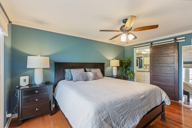 bedroom featuring wood finished floors, a barn door, ceiling fan, and crown molding