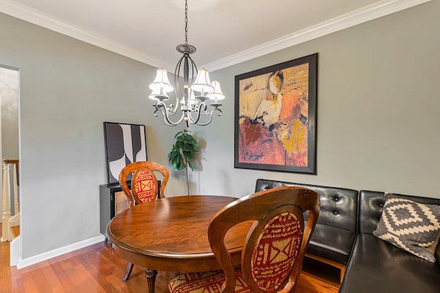 dining room featuring baseboards, wood finished floors, an inviting chandelier, and crown molding