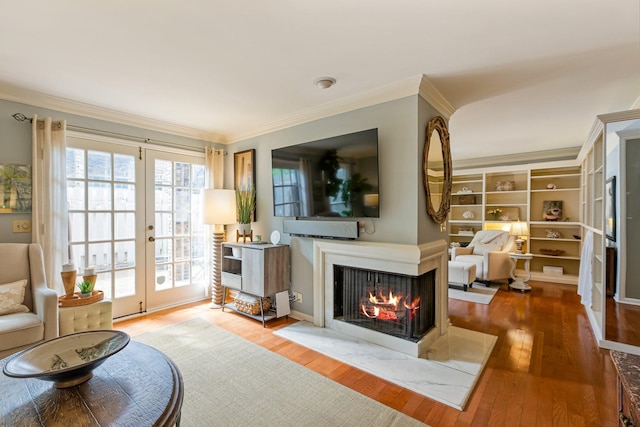 living area with a multi sided fireplace, wood finished floors, french doors, and crown molding