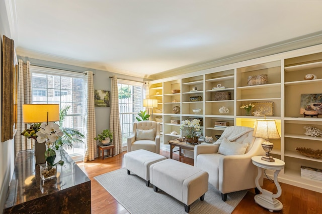 living area with wood finished floors, crown molding, and built in shelves