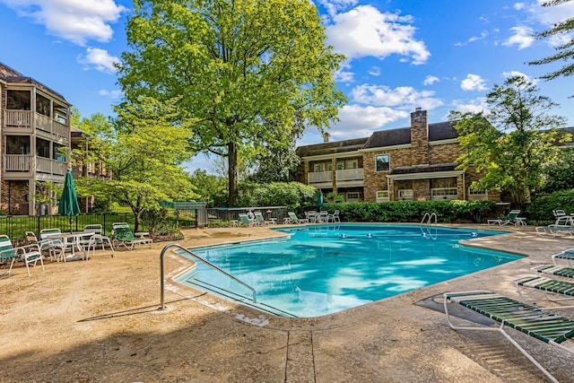 community pool with a patio and fence