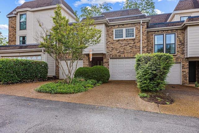 view of property featuring brick siding, driveway, and an attached garage