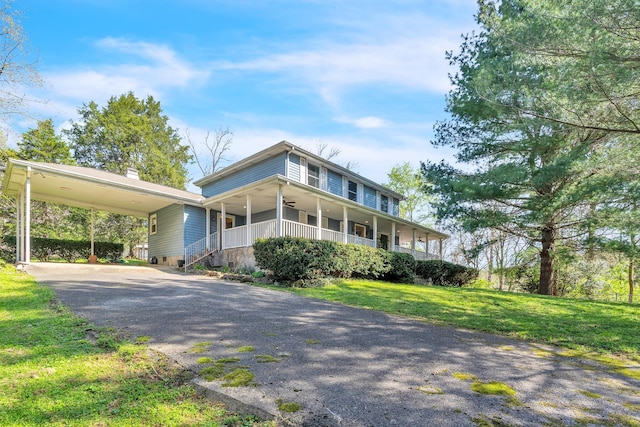 farmhouse-style home featuring covered porch, ceiling fan, an attached carport, driveway, and a front lawn