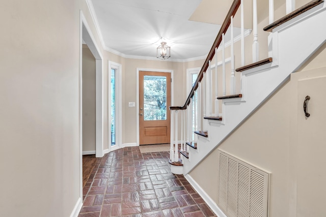 entryway featuring an inviting chandelier, stairway, brick floor, visible vents, and crown molding