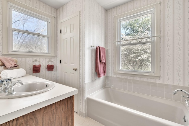 bathroom featuring a bath, tile patterned flooring, wallpapered walls, and a sink
