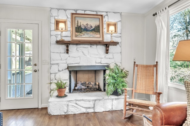 sitting room featuring a fireplace, wood finished floors, plenty of natural light, and crown molding