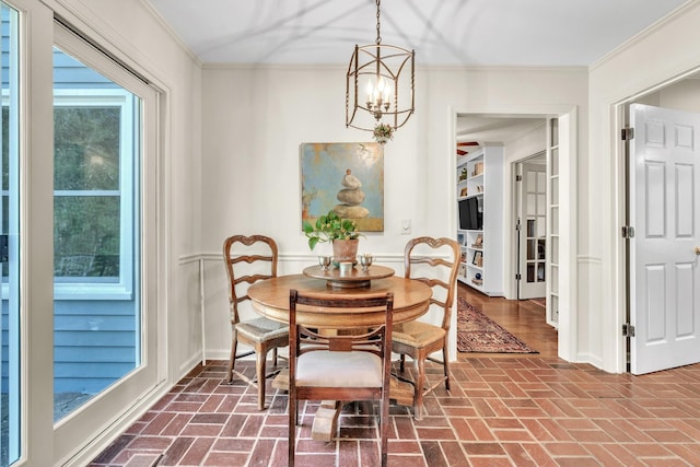dining area with ornamental molding, brick floor, and an inviting chandelier