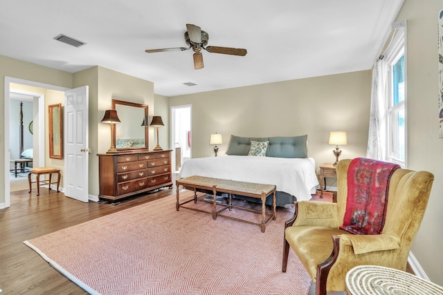 bedroom with wood finished floors, ceiling fan, visible vents, and baseboards