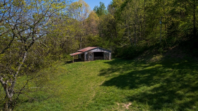 view of yard featuring a pole building, an outbuilding, and a wooded view