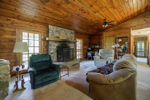 carpeted living room featuring a fireplace, wood walls, vaulted ceiling, and plenty of natural light