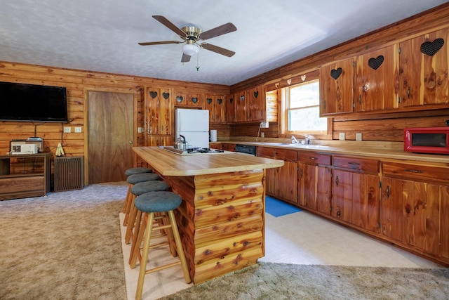 kitchen with brown cabinets, light colored carpet, ceiling fan, butcher block counters, and white appliances