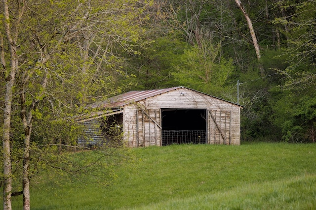 view of outbuilding featuring a wooded view and an outbuilding
