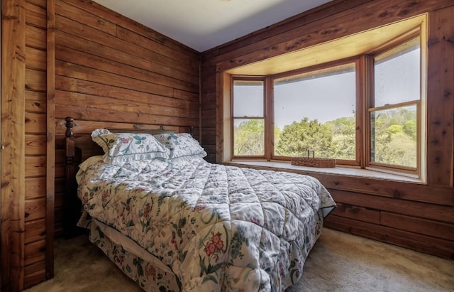 bedroom featuring carpet flooring, wooden walls, and multiple windows