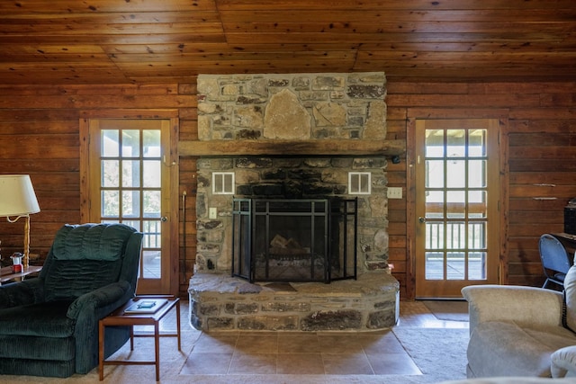 living area featuring wood ceiling, visible vents, wood walls, and a stone fireplace