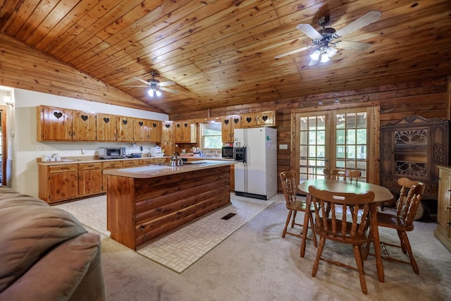 kitchen with lofted ceiling, brown cabinets, white refrigerator with ice dispenser, light colored carpet, and a ceiling fan